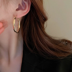 Close-up of elegant minimalist gold geometric hoop earring worn by a female model