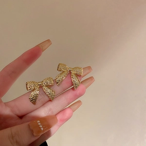 Elegante goldene Schleifen-Ohrstecker mit Metalloberfläche, zur Größenansicht gehalten