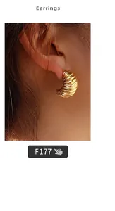 Close-up of golden C-shaped hoop earrings with a textured ribbed finish on model