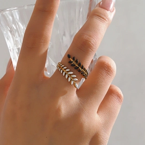 Gold leaf ring with black and white enamel finish worn by a model in soft light