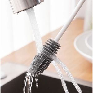 Long handle silicone cup brush with grey head being rinsed under running water