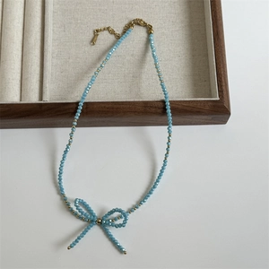 Detail of handmade sky blue faceted crystal beaded necklace with a woven bow pendant