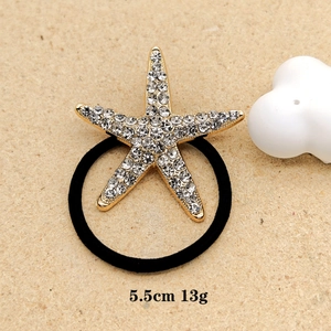 Close-up of golden starfish hair tie with rhinestones on beige background, 5.5cm size