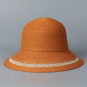 Detailed texture of orange raffia sun hat with elegant woven straw pattern details