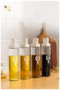 Detail of 500ml glass oil dispensers with automatic lids and labeling on wood surface