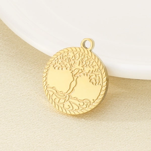 Macro shot of gold tree of life pendant on a beige fabric and ceramic plate