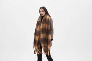 Detail of a thick brown checkered scarf with fringe tassels shown on a model