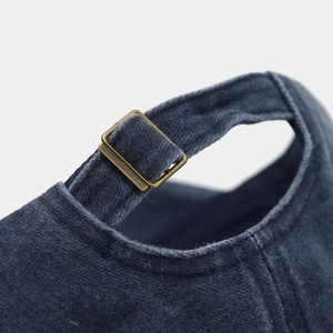 Detailed macro view of navy blue cotton cap with adjustable vintage bronze metal buckle