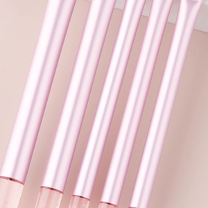 Detail of five mini makeup brushes with pink crystal glitter handles on a pink background