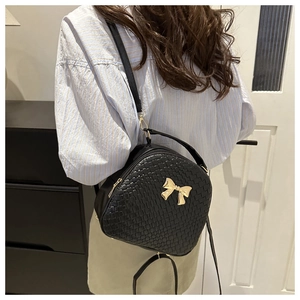 Dettaglio della borsa a tracolla nera intrecciata con elegante accessorio a fiocco dorato