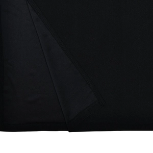 Close-up detail of the black knitted fabric texture and slit hem stitching on the dress