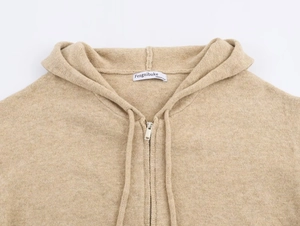 Detailaufnahme des Metallreißverschlusses und der Stricktextur dieses beigen Cardigans