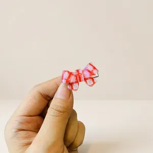 Close-up of mini red and white checkered bow hair clip with a metal alligator base