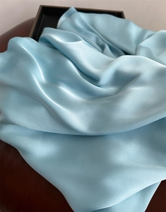 Close-up of smooth light blue satin fabric with elegant folds and glossy texture