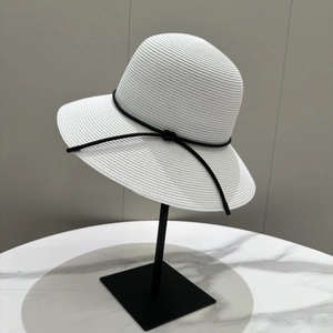 Détail d'un chapeau de soleil tressé blanc avec nœud en cordon noir sur support