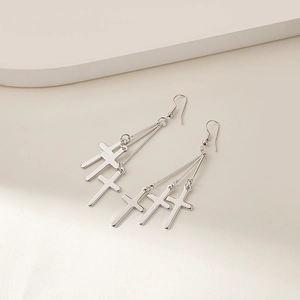 Detailed view of silver cross tassel earrings with polished metal geometric pendants