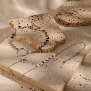 Elegant 925 sterling silver layered bracelets with round discs on natural stone background