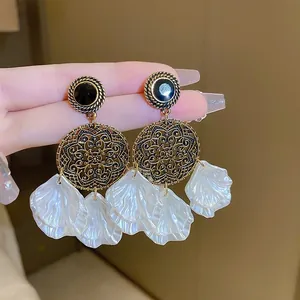 Detailed close-up of retro floral drop earrings with black stones and white shell petals