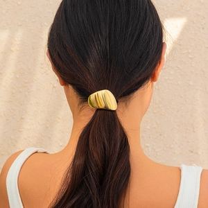 Detail of a minimalist gold geometric hair tie worn on a ponytail for a chic look