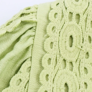 Close-up of light green blouse with elegant lace crochet details and pleated lantern sleeves