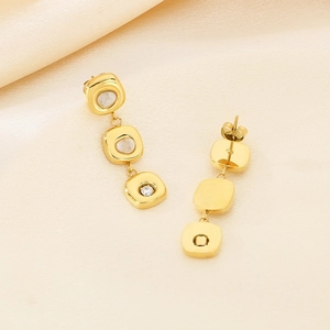 Detailed view of long 18K gold earrings with cushion-cut cat-eye stones and cubic zirconia
