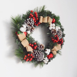 Detail of Christmas wreath with pine cones, red berries, cotton balls and burlap bow