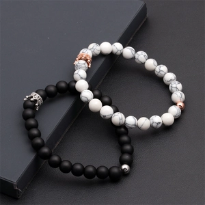 Detailed shot of black lava stone and white marble beaded bracelets with crown charms