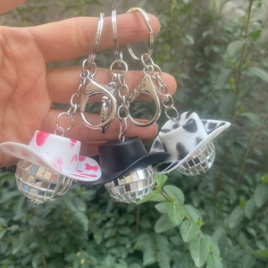 Drei Disco-Kugel-Schlüsselanhänger mit rosa gefleckten, schwarzen und weißen Cowboyhüten