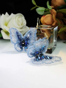 Detail of handmade crystal butterfly earrings with blue gradient beads and gold ear hooks