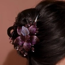 Detail view of purple floral hair claw clip with rhinestones worn by female model