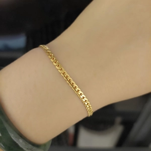 Close-up of golden titanium steel Cuban link bracelet on wrist showing classic weave