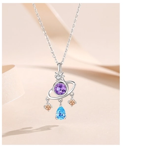 Macro shot of silver planetary pendant with purple, blue, and amber zircons on satin