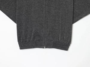 Detail showing the dark grey knit fabric texture and high-quality metal zipper on the hem