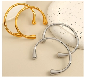 Dettaglio di bracciali rigidi aperti in oro e argento con estremità a forma di goccia