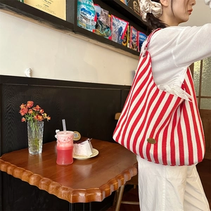 Détail du grand sac cabas rayé rouge et blanc avec plaque logo en métal doré