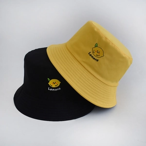 Close-up of lemon embroidery and textured cotton fabric on black and yellow bucket hats