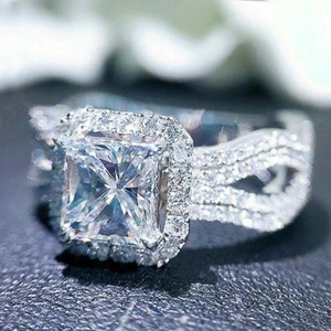 Sparkling princess cut halo engagement ring with pavé stones and crossover band