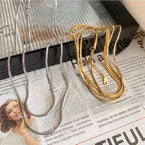 Titanium steel square snake chain necklaces in gold and silver finish on a newspaper
