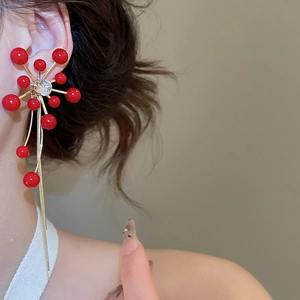 Detail of red bead flower drop earrings with golden tassels and central crystal
