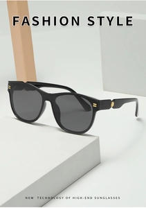 Detail view of oval oversized sunglasses with golden metal accents and dark grey lenses