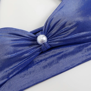 Macro detail of royal blue bikini top with pleated knot design and white pearl ornament