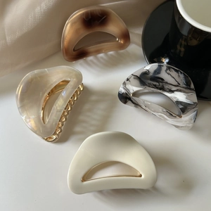Detail of four acetate hair claws in tortoise shell and marble patterns with gold spring
