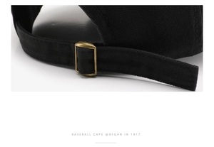 Detail of adjustable metal slider buckle on black cotton twill baseball cap back strap