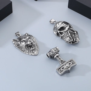 Detailed close-up of Viking wolf head, skull, and Mjolnir hammer steel pendants set