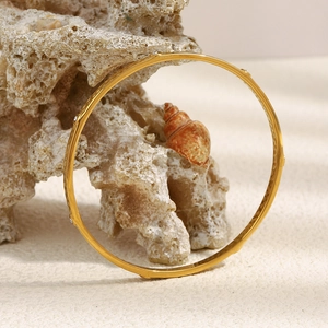 Detail of 18K gold plated hammered bangle with small zircon studs on coral stone
