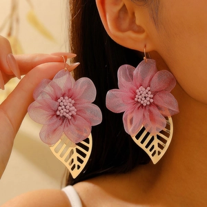 Orecchini a fiore in tessuto rosa con foglie dorate indossati da una modella alla moda