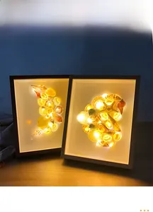 Detail view of DIY seashell shadow box with warm LED lighting and wooden frame