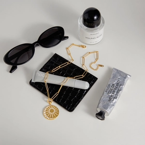 Detail of a 18k gold sunburst medallion necklace with zircon inlay on a minimal flatlay