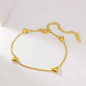 Detailed macro view of gold heart charm bracelet with starburst diamonds and lobster clasp
