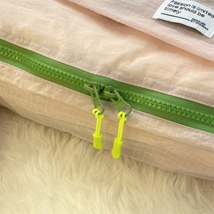 Detail of pink waterproof travel cube featuring neon yellow handles and green zippers